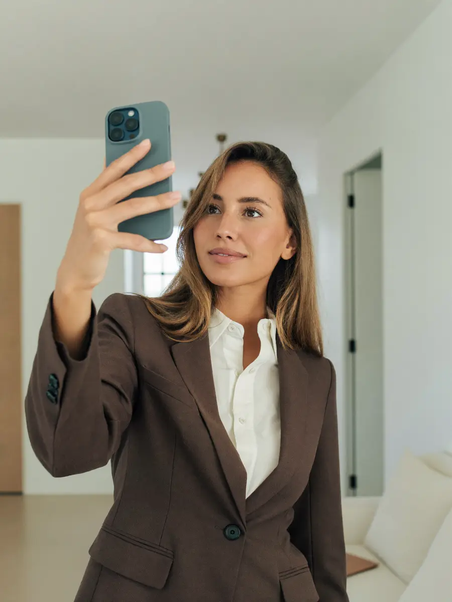 A woman holding up her phone to take a verification selfie